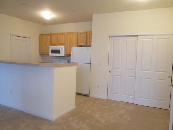 A kitchen with a white refrigerator and brown cabinets.
