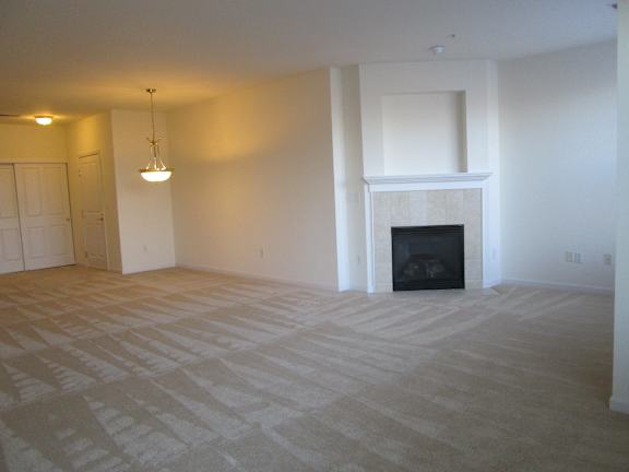 A large, empty room with a fireplace and a chandelier.