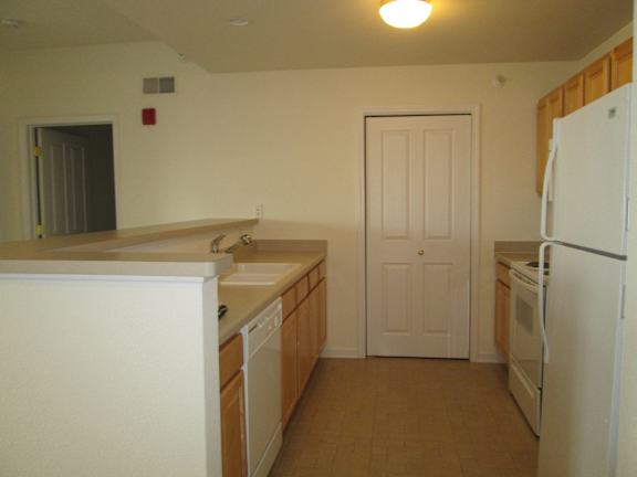 A kitchen with white appliances and wooden cabinets.
