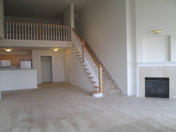 A living room with a fireplace and a staircase.