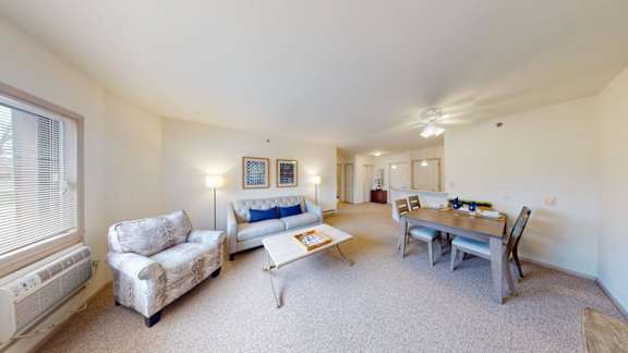 A living room with a couch, chairs, and a dining table.