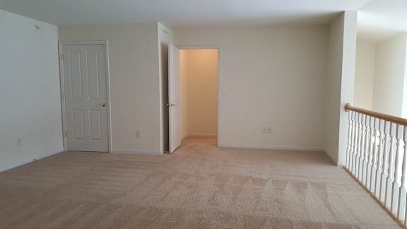 A room with a carpeted floor and a door on the left.
