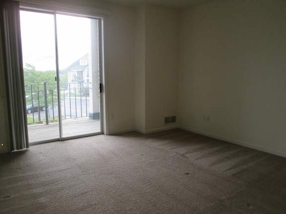 A room with a carpeted floor and a sliding glass door.