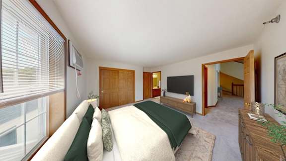 A bedroom with a large bed and a window with blinds.