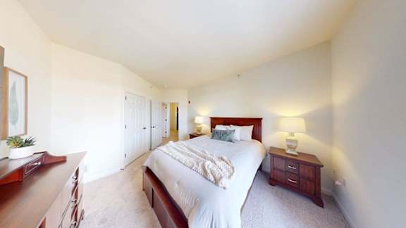 A bedroom with a large bed, a nightstand, and a dresser.