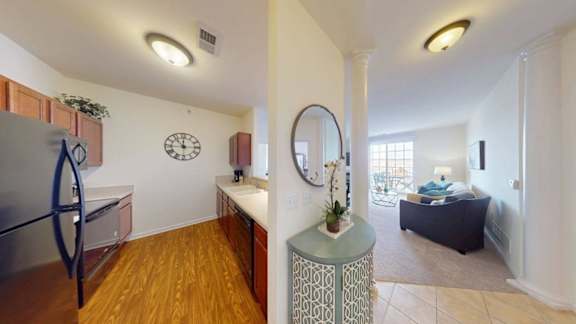 A kitchen with a refrigerator and a dining area with a table and chairs.