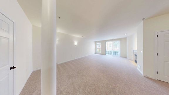 A large, empty room with white walls and carpeted floor.