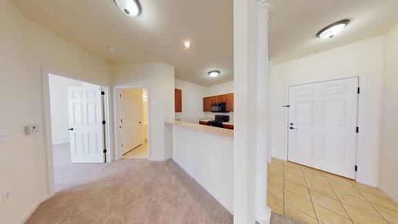 A spacious room with white walls and a carpeted floor.
