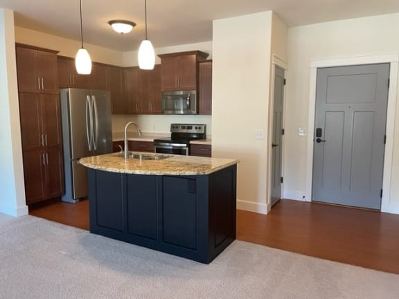 a kitchen with a granite counter top and a stainless steel refrigerator