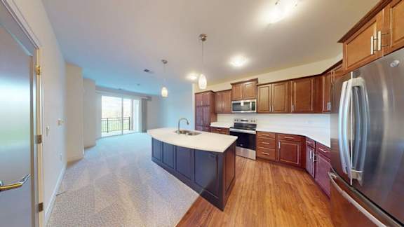 A kitchen with wooden cabinets and a stainless steel refrigerator.