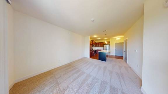 A long hallway with a carpeted floor and a door on the right side.