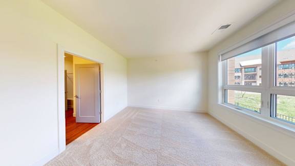 A room with a carpeted floor and a doorway leading to another room.