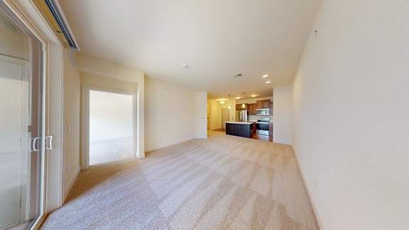 A long, empty hallway with a carpeted floor and a sliding glass door.