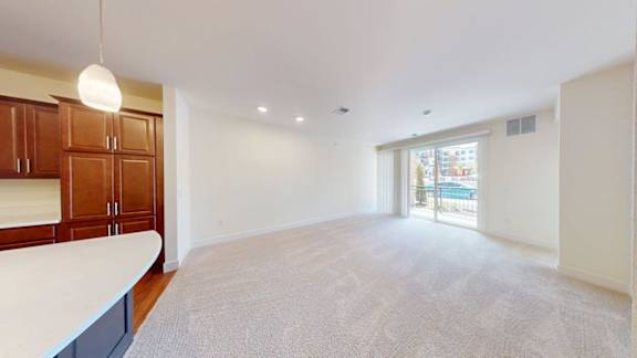 A spacious living room with a carpeted floor and a large window.
