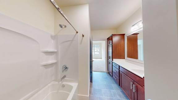 A white bathroom with a tub and wooden cabinets.