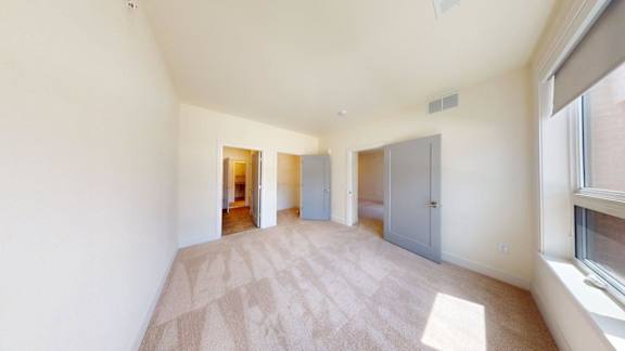 A room with a carpeted floor and a window on the right side.