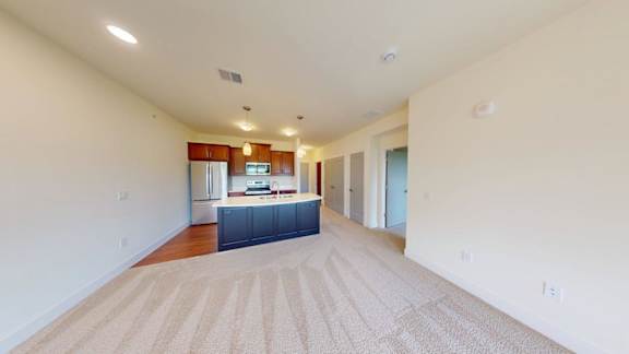 A spacious room with a kitchen area in the background.