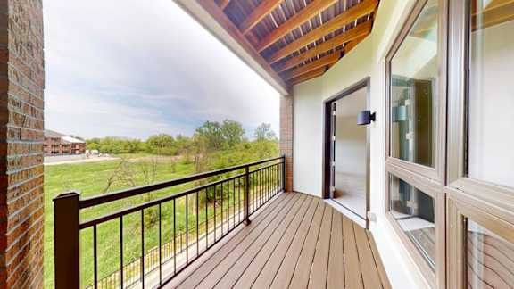 A balcony with a wooden floor and a glass door.