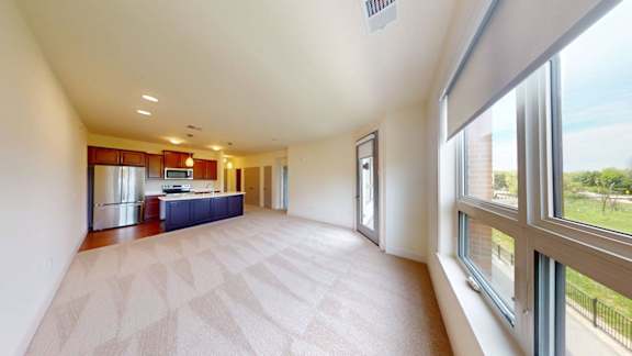 A spacious living room with a kitchen in the background.