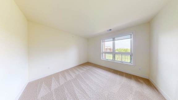 A room with a window and a carpeted floor.
