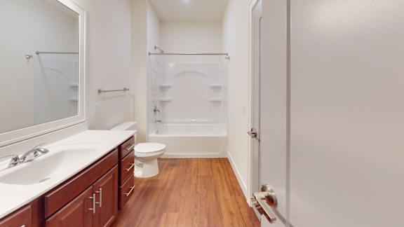 A white bathroom with a wooden floor and a white toilet.
