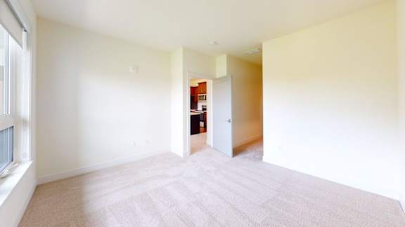 A room with a carpeted floor and a doorway leading to another room.
