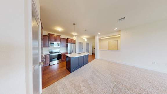 A spacious living room with a kitchen in the background.
