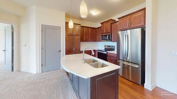 A kitchen with a white countertop and wooden cabinets.