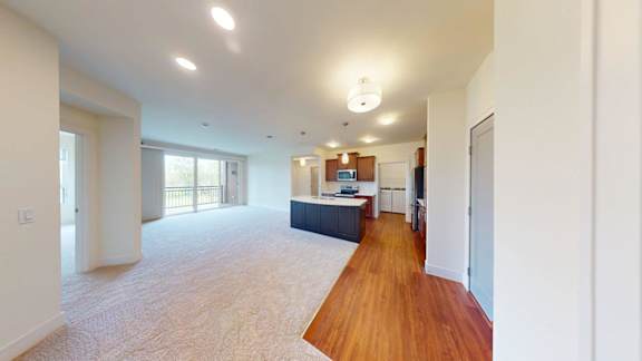 A spacious living room with a long wooden floor and white walls.