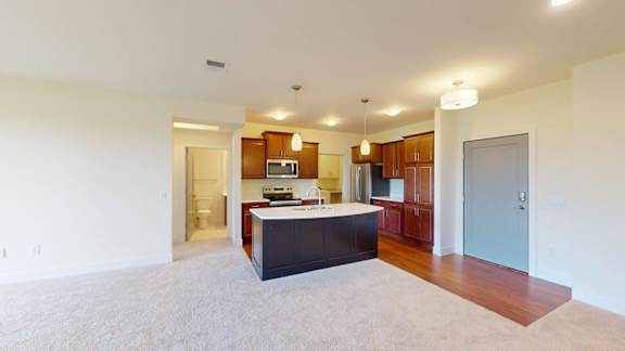 A kitchen with a counter and cabinets is visible from the living room.