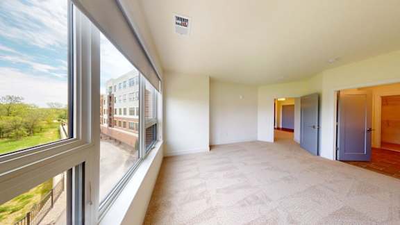 A large empty room with a view of a building outside the window.