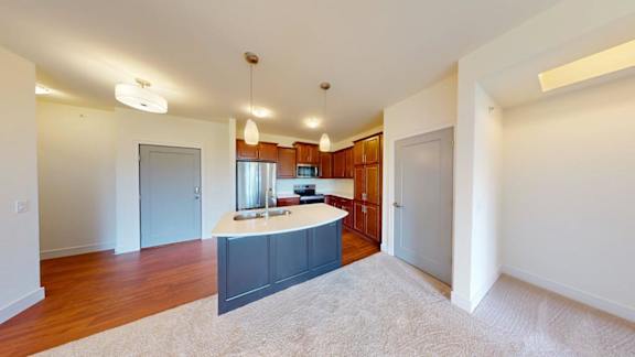 A spacious living room with a kitchen in the background.