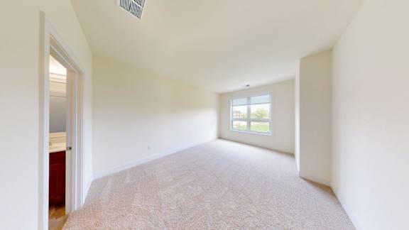 A room with a carpeted floor and a window letting in natural light.
