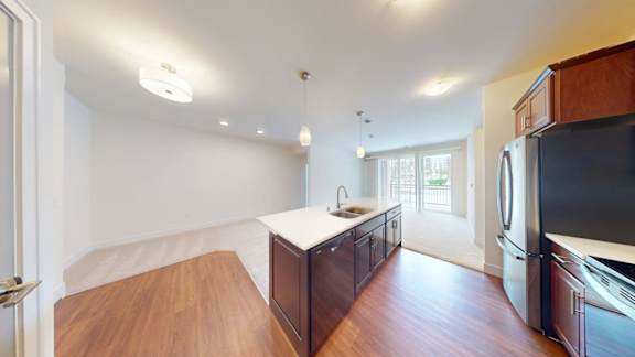 A kitchen with dark wood cabinets and a black fridge.