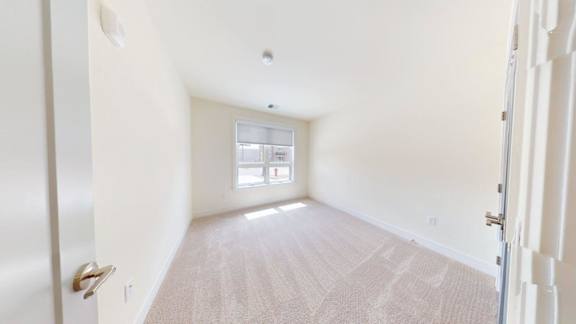 A room with a carpeted floor and a window.