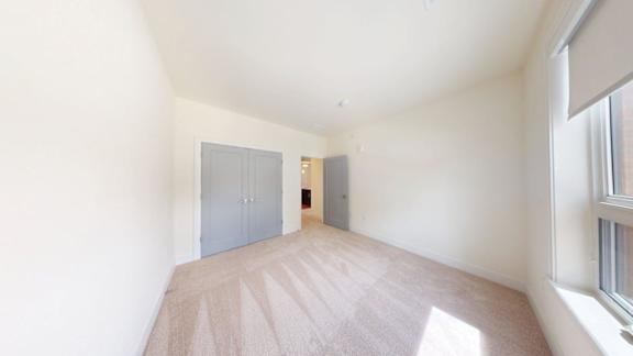 A room with a carpeted floor and two doors.