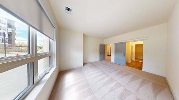 A spacious room with a large window and a tiled floor.
