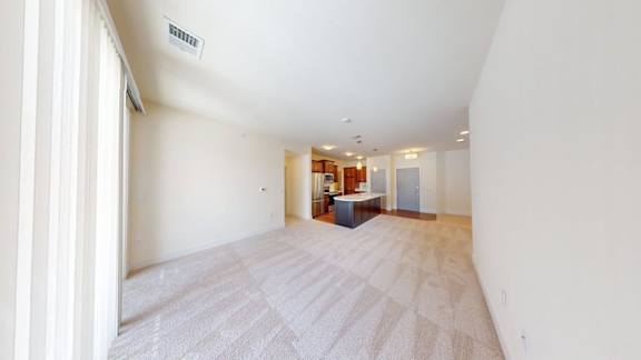 A large, empty room with a carpeted floor and a doorway leading to another room.