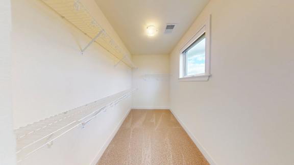 A long, narrow room with a window and a white wall on the left side.