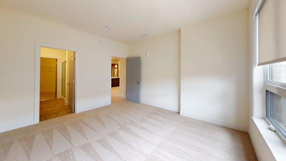 A room with a carpeted floor and a doorway leading to another room.