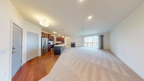 A large, empty room with a carpeted floor and a window on the far wall.