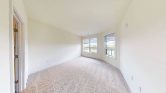 A room with a carpeted floor and two windows.