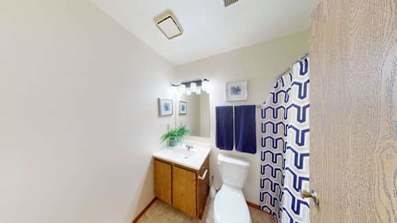 A small bathroom with a toilet, sink, and shower curtain.