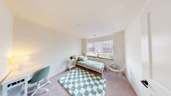 A white room with a green chair and a hanging swing.