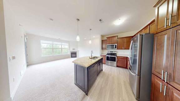 A kitchen with wooden cabinets and a black island.