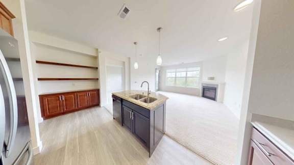 A kitchen with a sink, cabinets, and a refrigerator.