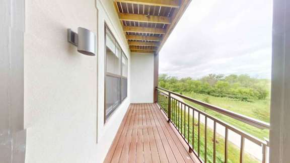 A balcony with a wooden floor and a metal railing.