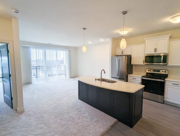 an empty kitchen and living room with a sink and refrigerator