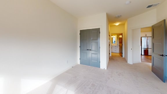 an empty room with a blue door and a hallway to a kitchen