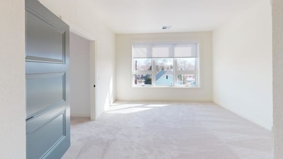 an empty room with a window and a blue door